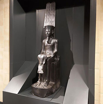 C'est une des œuvres majeures du musée du Louvre. Le dieu Amon est assis sur un trône. Il est représenté sous forme humaine. On le reconnaît à son casque plat surmonté de hautes plumes. Des parures soigneusement détaillées tel qu’un collier et des bracelets, ornent son cou et ses bras. Il tient par les épaules le roi qui est debout. Le souverain porte le costume des prêtres d'Amon. Le groupe a subi de nombreux dommages. La tête du roi a été détruite et ses bras sont manquants. Les mains d’Amon ont aussi été supprimées. Le pilier dorsal est recouvert d’une inscription. Les cartouches royaux qui s’y trouvaient ont été complètement effacés à l’exception des noms des divinités qu’ils contenaient.